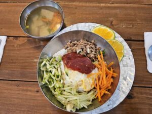 ビビンバ、スライスしたレモン、豆腐スープが盛られた昼食