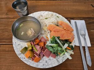 チャーハン、野菜とスパム炒め、フルーツ、チキンスープが盛られた朝食