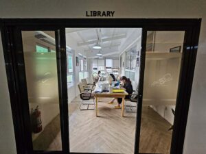 大きなテーブルがある図書室で自習や仕事をする学生たち