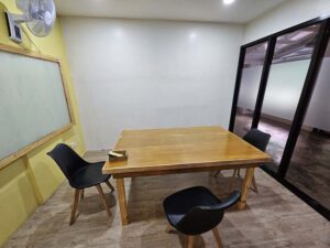 大きなホワイトボードと木製テーブルがあるグループ教室