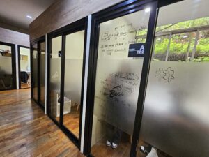 木製床の廊下から見たガラス張りのマンツーマン教室