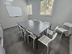 窓が2つあるグループクラスの教室、椅子、机、ホワイトボードあり