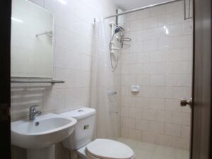 洗面台、鏡、トイレが完備されたタイル張りのバスルーム