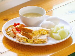 朝食のサンドイッチ、ゆで卵、スープ、メロン、野菜炒め
