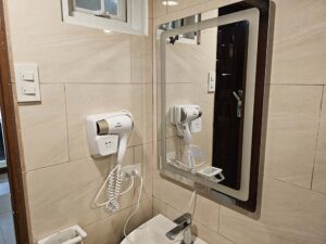 共用バスルームの壁に設置された照明付き鏡とドライヤー