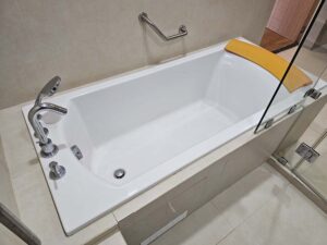 ハンドシャワーとヘッドレストが付いた大きめのバスタブ