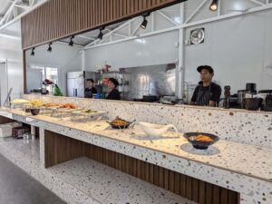 昼食ビュッフェに並んだ複数の料理とキッチンスタッフ