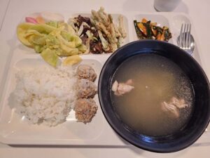 牛肉炒め、天ぷら、ミートボール、サラダ、スープが盛られた夕食