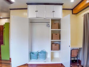 収納棚とバスケットが備わった扉付きクローゼットと勉強机がある3人部屋