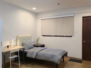 窓際にシングルベッド、ナイトテーブル、勉強机が配置されたスタジオルーム