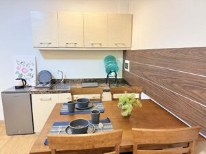 ダイニングテーブル、冷蔵庫、シンク、電気コンロのある簡易キッチンエリア