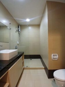 カウンター付きの洗面台とガラスで仕切られたシャワーエリアのあるバスルーム