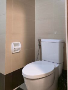 タイル張りのバスルームの一角に設置されたトイレとペーパーホルダー