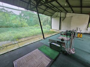 ゴルフクラブとボールが設置された屋根付きゴルフ練習場