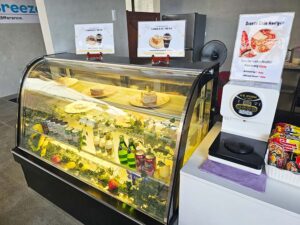ショーケースにワッフルとパン、ソフトドリンクが並ぶ校内カフェ