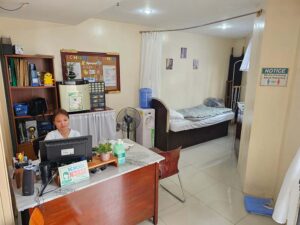 ベッドのある校内クリニックでPC作業をしている看護師