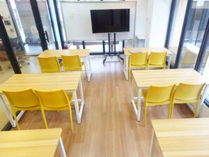 ガラス窓で囲われた部屋に2人掛けのテーブルが並んだ自習室1