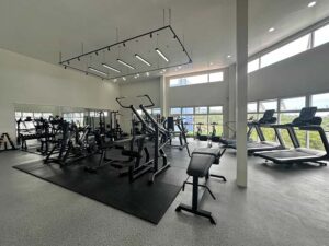 有酸素運動と筋力トレーニングの器具が揃った大きな窓のあるジム