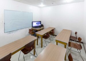 長机、椅子が並び、講師の机にPCが設置された大人数対応の教室