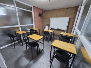 大きなホワイトボードと6台のテーブルが並んだグループクラスルーム