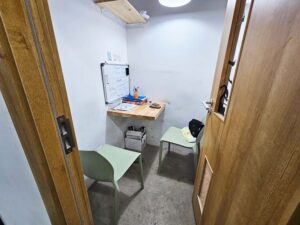 壁付けの机と椅子がL字に配置されたマンツーマン教室