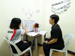 文法の体験授業で白板を使って説明する講師と、発言している生徒