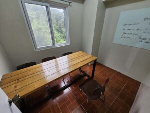 緑を見渡せる窓と長机があるグループクラス教室