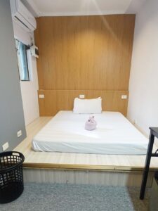 高床にマットレスが敷かれ、枕元にコンセントがある1人部屋