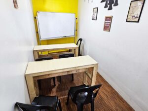 大きめの白板と、2人掛けの木製テーブルが2台並んだグループ教室