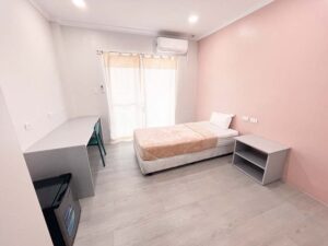 ベッドとサイドテーブル、エアコン、冷蔵庫が設置された1人部屋