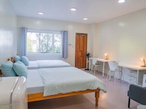 2つのベッドと勉強机、冷蔵庫があるシングル利用の部屋