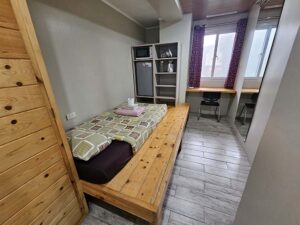 ベッド、冷蔵庫、電子レンジ、ケトルが備わった左側の1人部屋