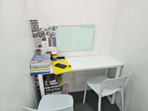 白板と机、横並びに配置された椅子のあるマンツーマン教室