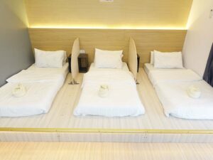 高床に3枚のマットが並び、枕元に仕切り板が設置された3人部屋