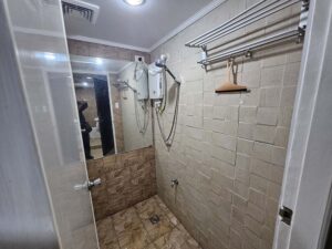 大きな鏡とシャワー、タオルハンガーのある共用シャワールーム
