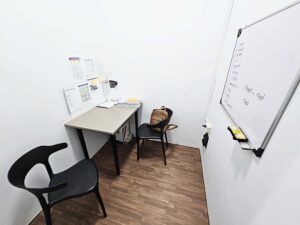 文法資料が壁に貼られ椅子がL字型に配置されたマンツーマン教室