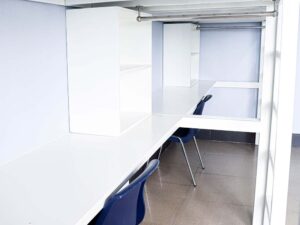 収納棚とハンガーラックが備えられた、2段ベッド下段の机部分
