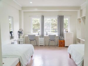 離れて設置されたベッドと机、冷蔵庫、収納棚のある2人部屋