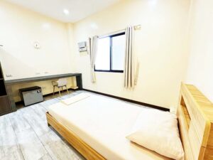 ベッドの向かい側にカウンターテーブルと冷蔵庫が設置された1人部屋