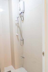 シャワーヘッド、温水器、蛇口があるシャワールーム
