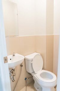 ベージュタイルの腰壁とトイレ、洗面台のあるトイレットルーム