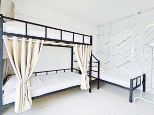 カーテン付き二段ベッドとシングルベッドが配置された2+1人部屋