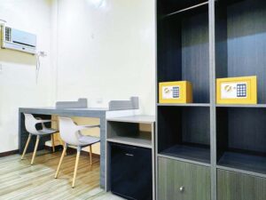 2人用の机と椅子、冷蔵庫、ワードローブ、金庫のある2人部屋