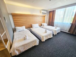 大きな窓があり、ベッドが3台並んだトリプルルーム