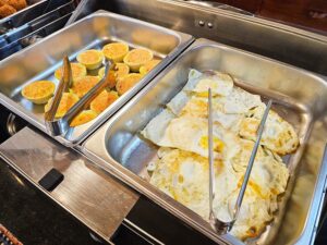 朝食のビュッフェトレイに盛られた目玉焼きとエッグマフィン
