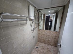 温水器とシャワー、蛇口、タオルハンガーのあるシャワールーム