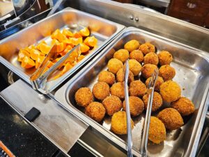 朝食カウンターに並べられたコロッケとカットオレンジ