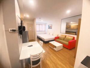 ベッドが3台並び、ソファー、テレビ、冷蔵庫が備わった3人部屋