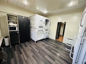 2台の二段カプセルベッド、クローゼット、冷蔵庫、電子レンジ、除湿器のある4人部屋