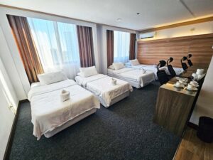 窓際に4台のベッドが横一列に並ぶ、奥行きのあるクワッドルーム